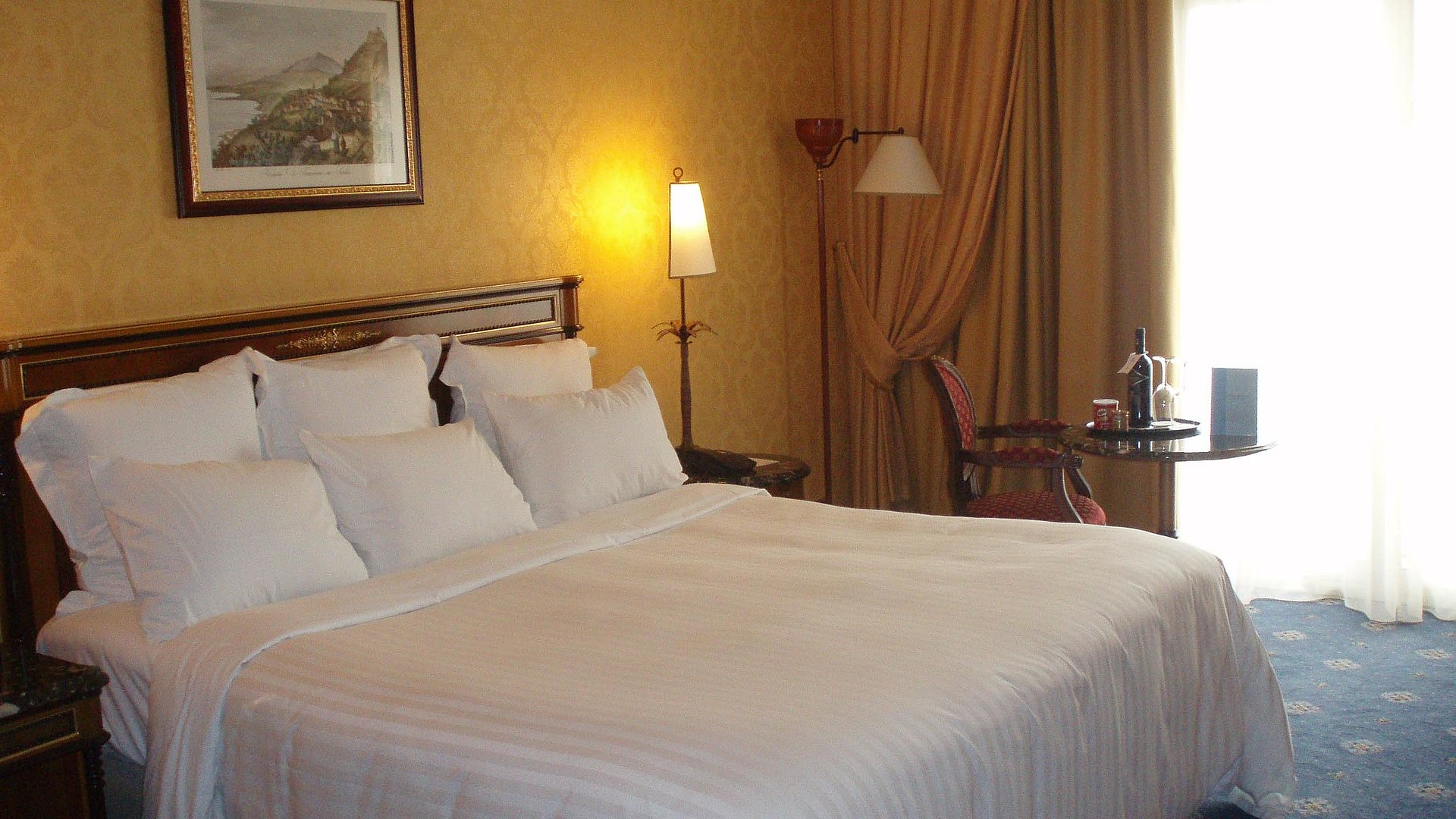 Hotels für Gruppen im Oberallgäu - sehr ordentliches Hotelzimmer im Antik-Stil mit warmer Nachttischlampe und Lichteinfall von außen durch weiße Gardinen