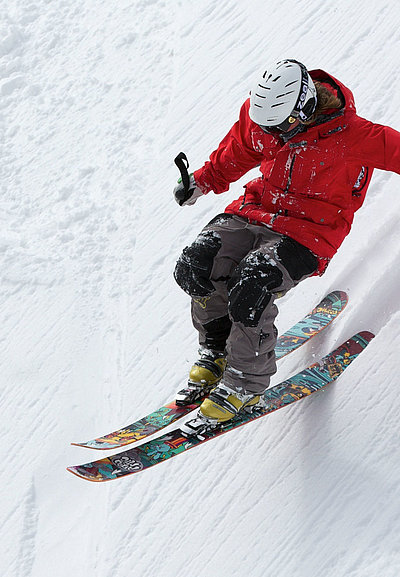Freizeit und Sport im Oberallgäu - Mann in Skiausrüstung fährt soeben Schnee-Hügel runter